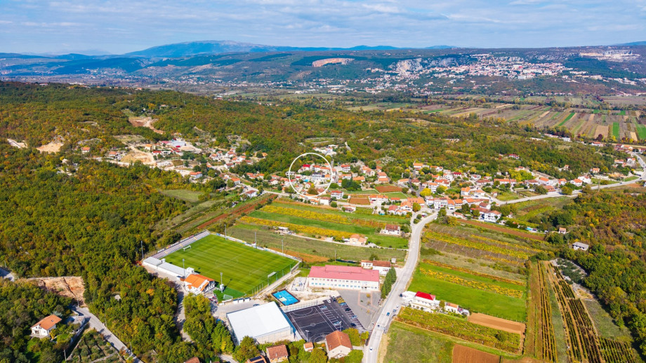 The villa (circled) is located in the peaceful village of Zmijavci, surrounded by agricultural fields and close to local amenities like a soccer field.