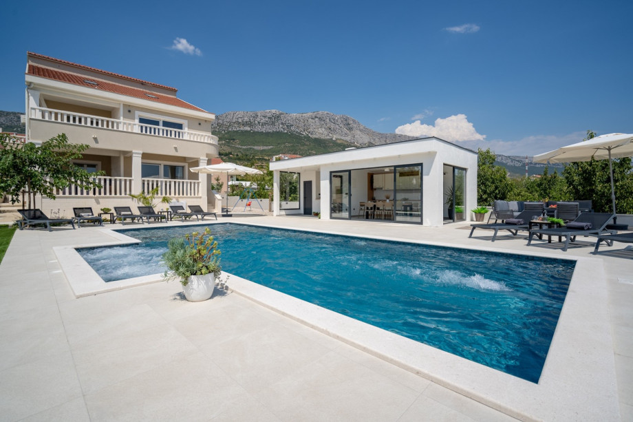 he spacious sun-deck area spreads on two levels, around the pool and a few steps below on the grassplot
