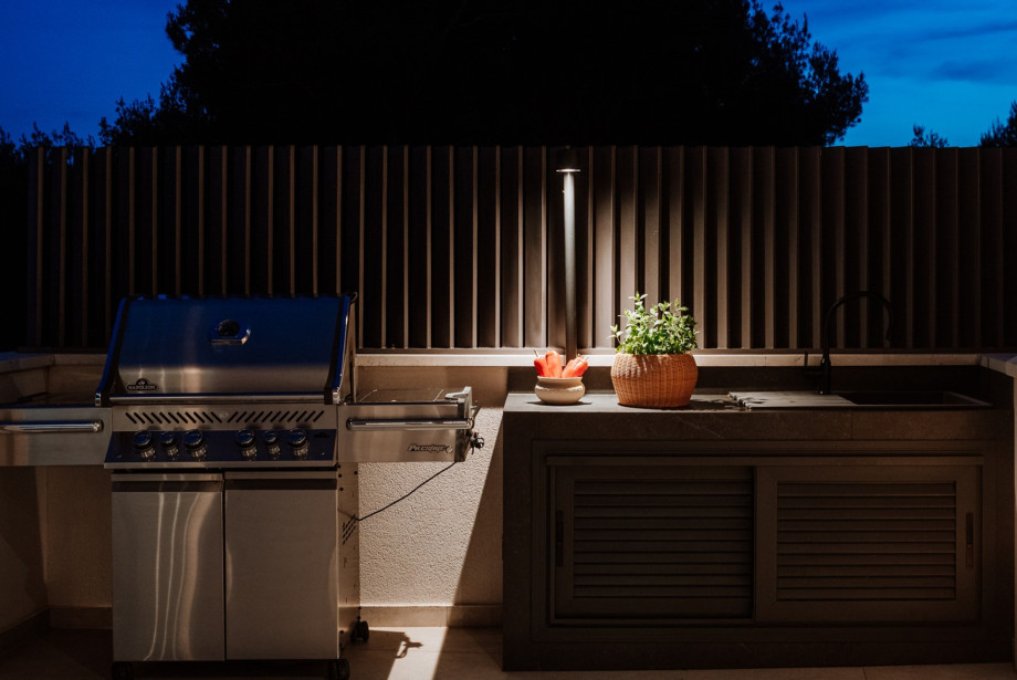 Outdoor dining area with a Napoleon gas Grill with a kitchen worktop with a sink next to it.